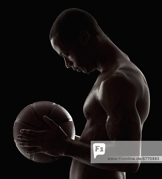 Studio shot of shirtless man holding basketball