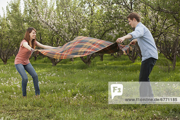USA  Utah  Provo  Young couple holding blanket in orchard