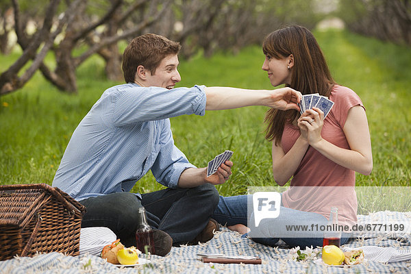 USA  Utah  Provo  Young couple playing cards during picnic in orchard