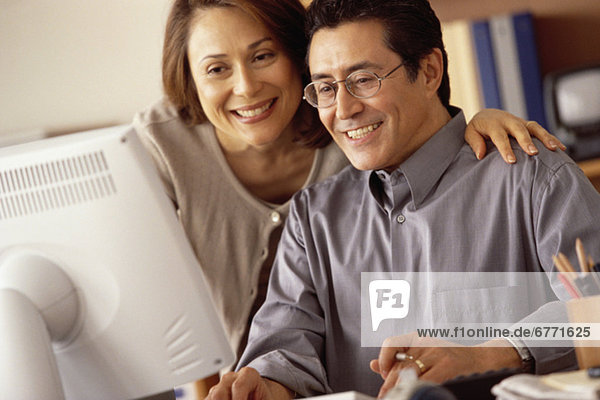 Couple working at computer in home office