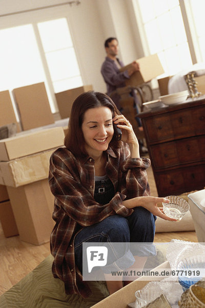 Woman talking on the phone while unpacking boxes