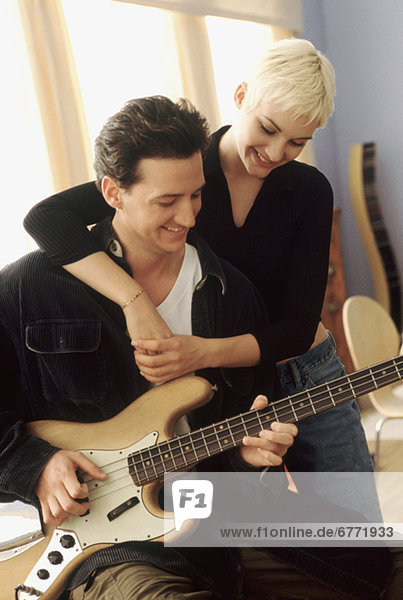 Woman listening to her boyfriend playing the electric bass