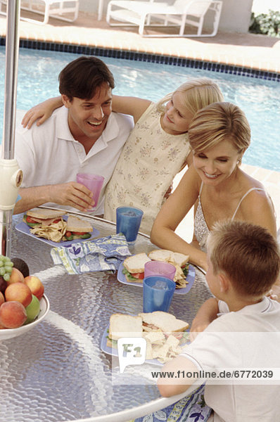 Family eating lunch by the pool