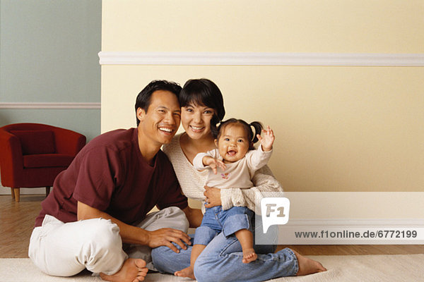 Happy parents sitting on the floor with their infant daughter