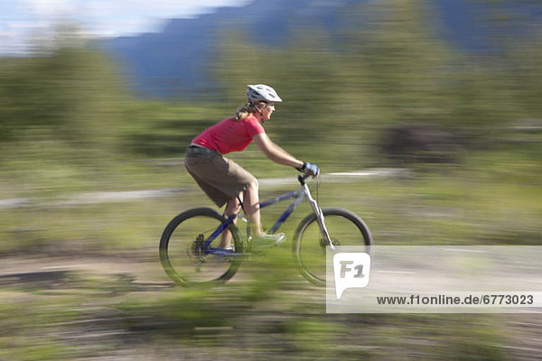 Canada  British Columbia  Fernie  Young woman riding on mountain bike