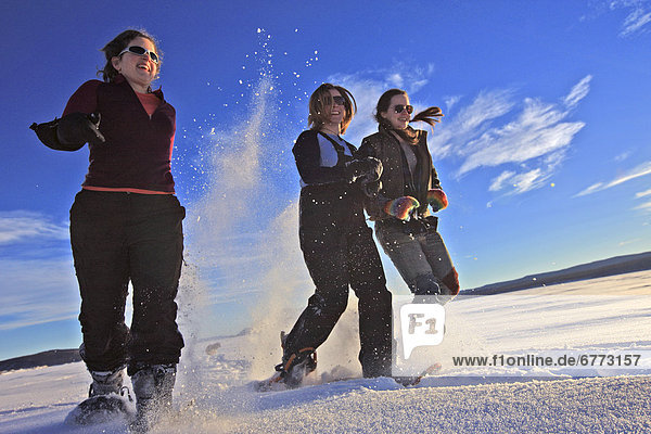 Women in snowshoes running across the frozen Teslin Lake  Yukon