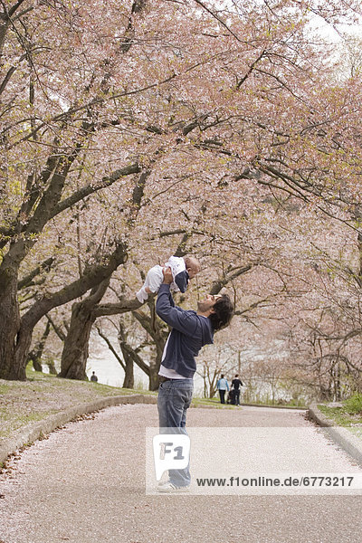 Man holding a baby on a tree lined path  High Park  Toronto  Ontario