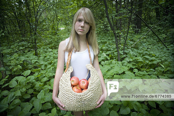 Girl with a bag of apples standing in a forest  Winnipeg  Manitoba