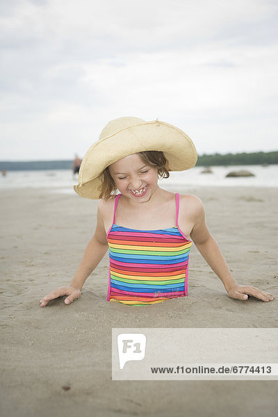 Girl laughing while buried in sand  Grand Beach  Manitoba