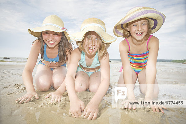 Three girls playing in sand  Grand Beach  Manitoba