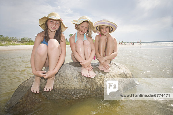 Three girls sitting on a rock  Grand Beach  Manitoba