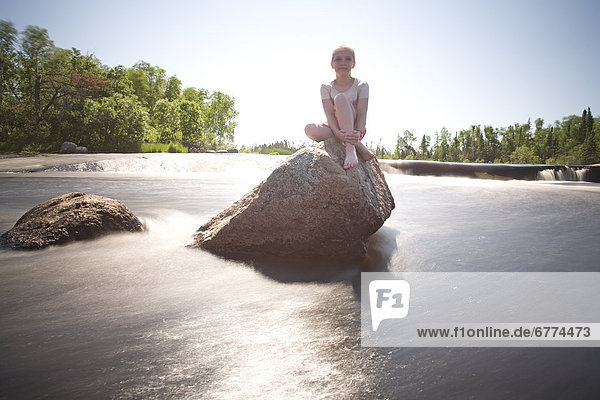 Girl sitting on a stone in a stream  Grand Beach  Manitoba