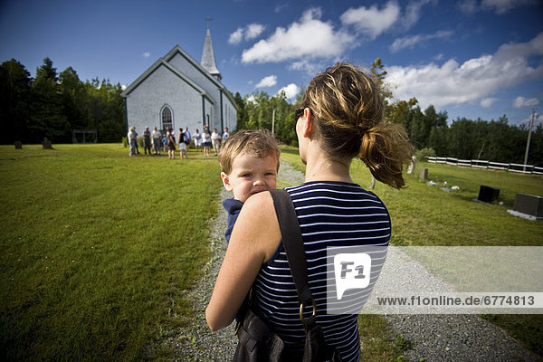 Mother carrying her young boy towards a small Catholic church in Merland  Antigonish County  Nova Scotia