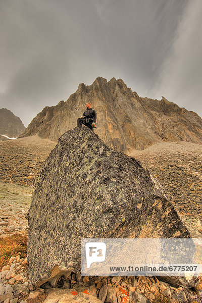 Hiker standing on a large rock  Tombstone Territorial Park  along the Dempster Highway  Yukon