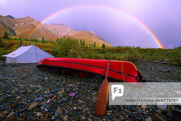 Canoe and Tent at a Campsite with a Rainbow and the MacKenzie Mountains in the Background in Autumn  Snake River  Whitehorse  Yukon