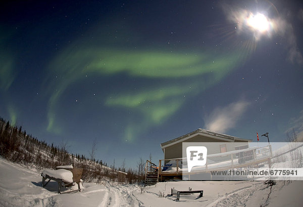 Aurora Borealis and Bright Moon over a Cabin  Tibbett Lake  outside of Yellowknife  Northwest Territories