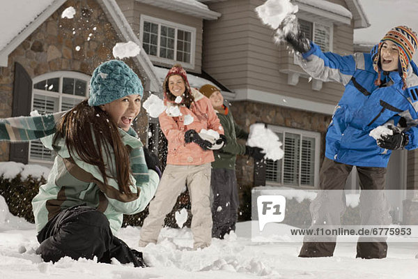USA  Utah  Provo  Boys (10-11  12-13) and girls (10-11  16-17) having snow ball fight in front of house
