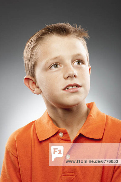 Portrait of boy (8-9) wearing polo shirt and looking away  studio shot