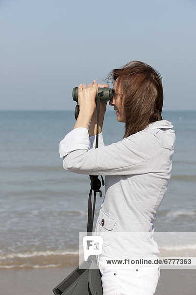 Woman on beach looking through binoculars