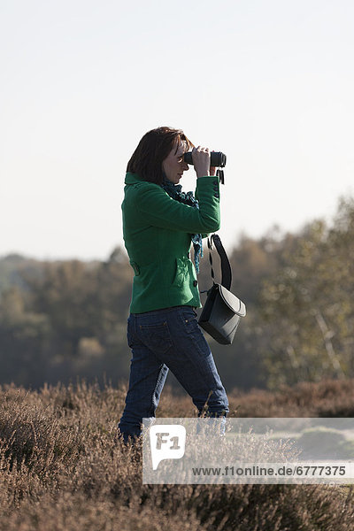 The Netherlands  Veluwezoom  Posbank  Woman in countryside looking through binoculars