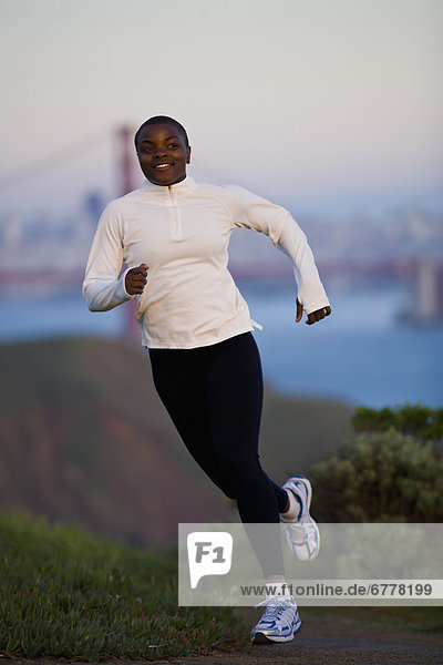USA  California  San Francisco  Woman jogging  Golden Gate Bridge in background
