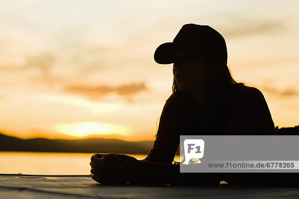USA  California  Silhouette of young woman relaxing on beach at sunset