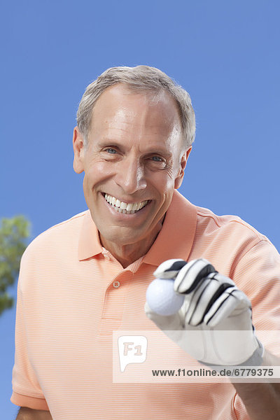 Portrait of senior man holding golf ball