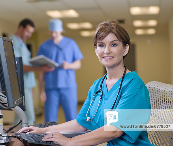 Female surgeon working on computer in hospital  colleagues in background