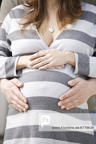 Man's hands on pregnant woman's belly