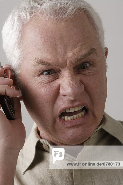 Portrait of angry senior man with mobile phone  studio shot