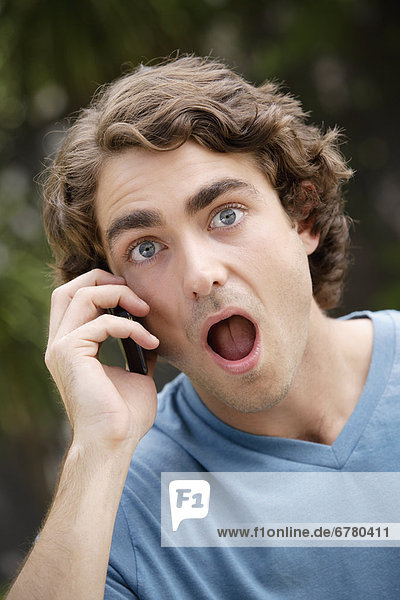 Portrait of young man talking on phone  with facial expression