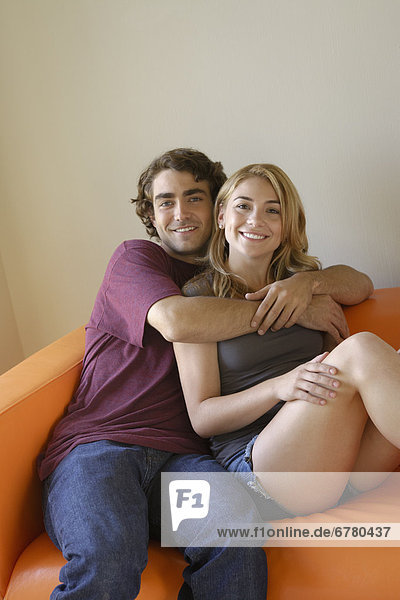 Portrait of young couple sitting on sofa