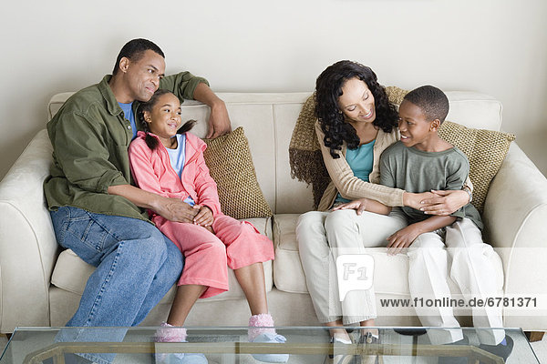 Parents with children (10-13) relaxing on sofa