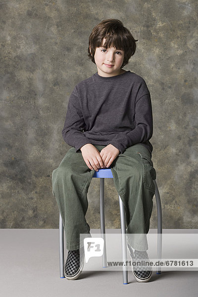 Smiling boy (6-7) sitting on chair  studio shot