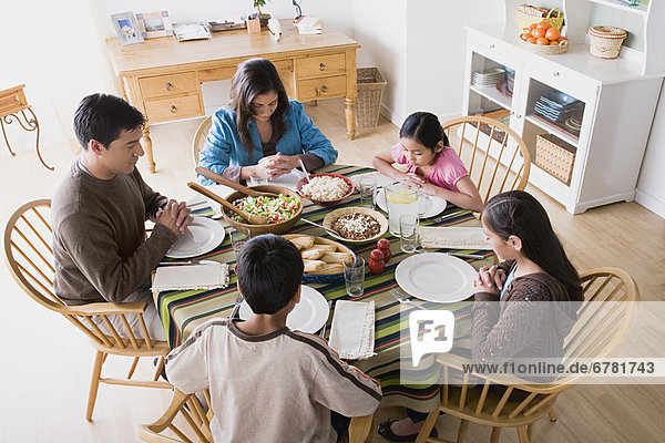 Family with three children (8-9  10-11) praying at table before dining