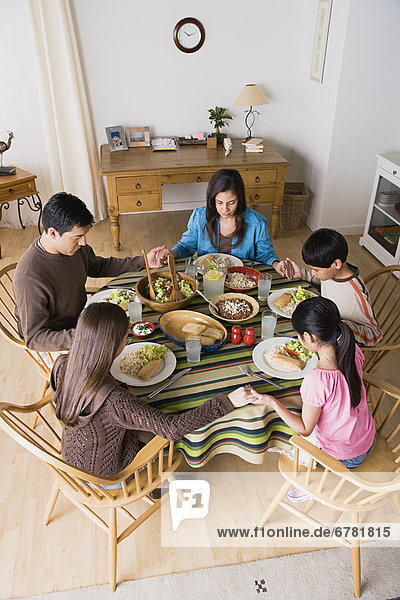 Family with three children (8-9  10-11) praying at table