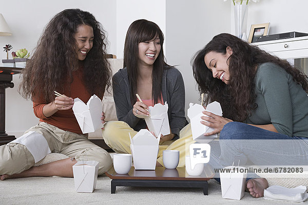 Three female friends eating take out food at home
