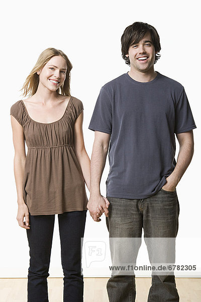 Studio portrait of young couple holding hands