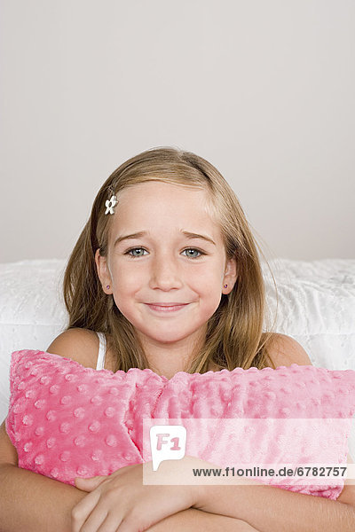 Portrait of smiling girl (10-11) with pillow