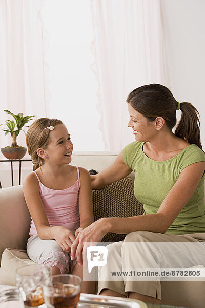 Mother talking to daughter (10-11) on sofa