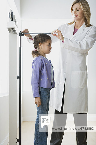 Doctor measuring girl (10-11)