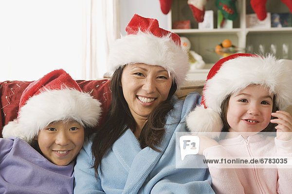 Portrait of mother with two daughters (10-11) wearing Santa hats