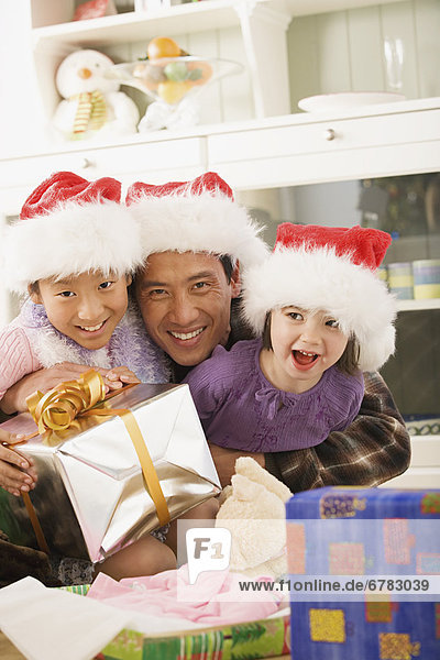 Portrait of father with two daughters (10-11) wearing Santa hats
