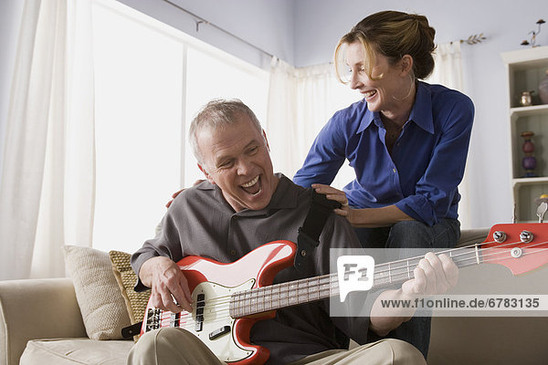 Man playing electric guitar with woman