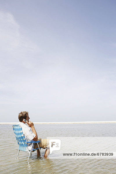 Man talking on cell phone in middle of water