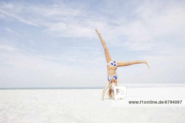 Teenage girl doing cartwheel in beach