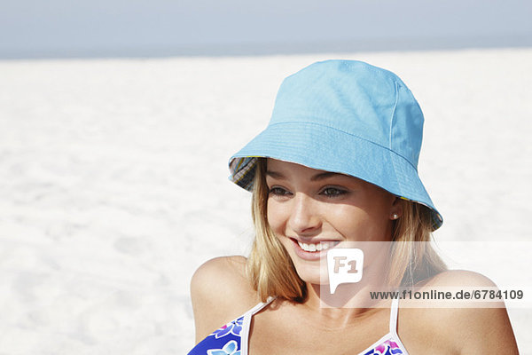 Teenage girl in hat sunbathing on beach