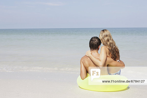 Couple sitting in inflatable ring in shallow ocean