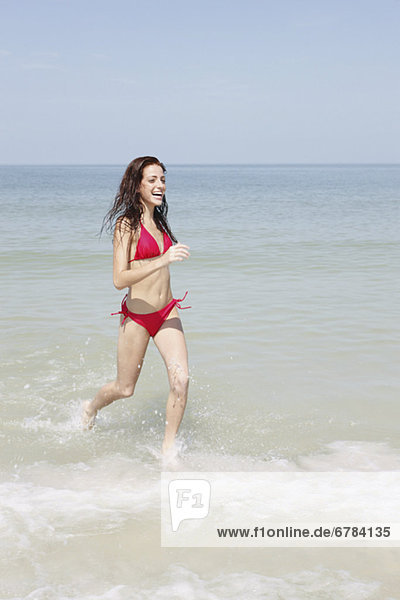Young woman running in ocean