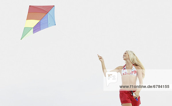 Young woman flying kite on beach